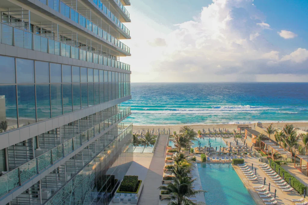 Infinity pool overlooking the Caribbean Sea at Secrets The Vine Cancun, with sleek loungers and sunset lighting.