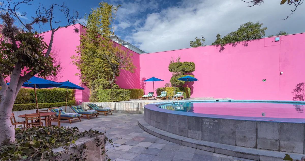 Elegant hotel facade at Camino Real Polanco, framed by lush greenery and modern architecture