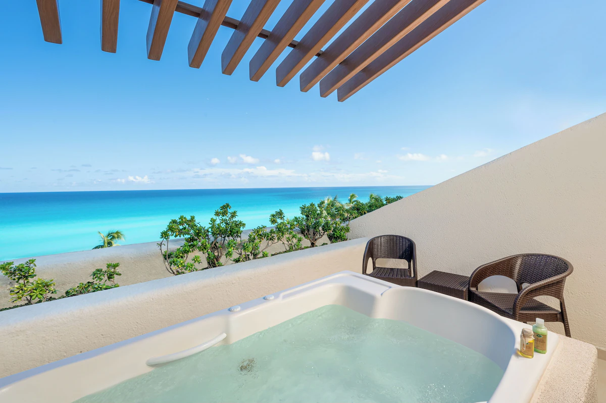 Beachfront view of Royal Solaris Cancun resort with palm trees, sun loungers, and turquoise ocean under a clear sky.