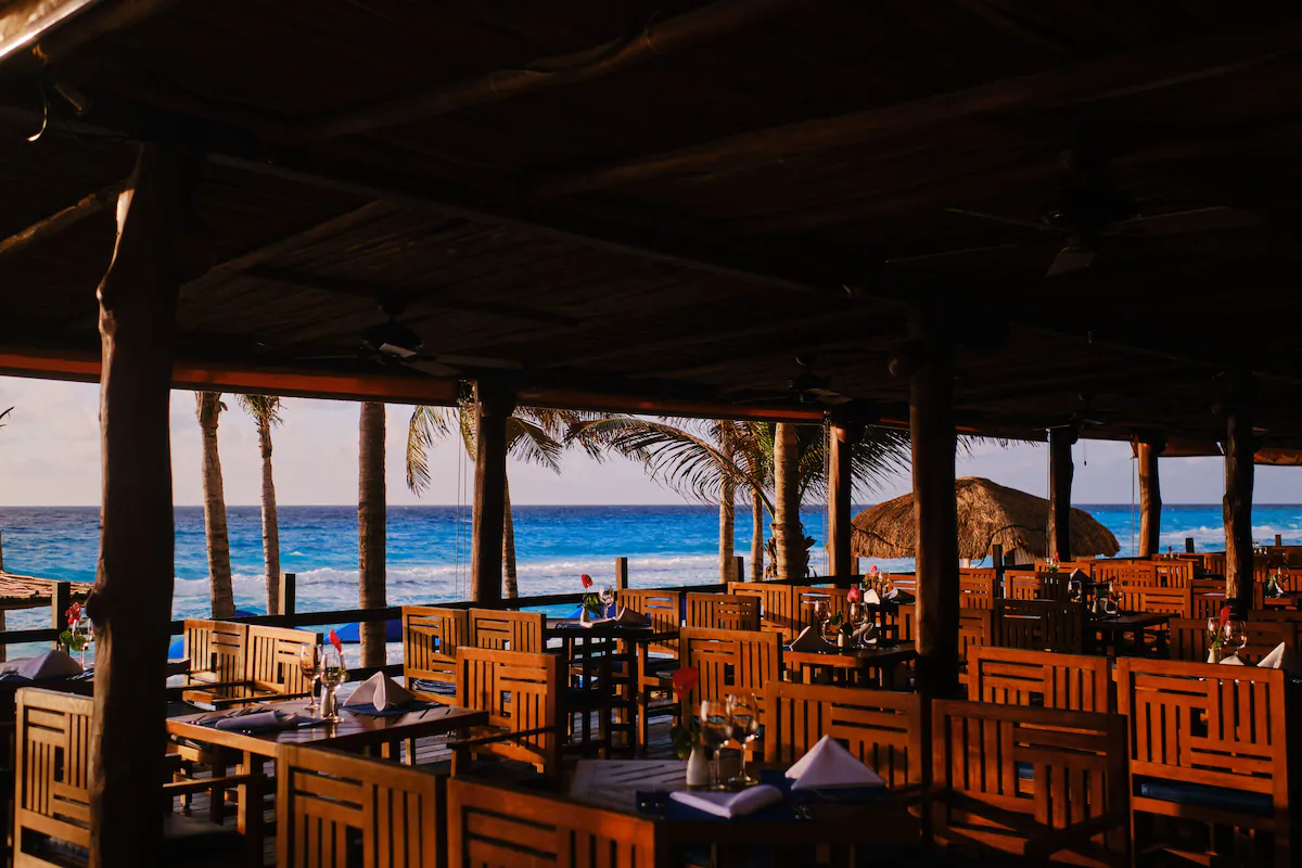 Modern beachfront hotel with infinity pool overlooking turquoise Caribbean waters near La Isla Shopping Mall in Cancun.