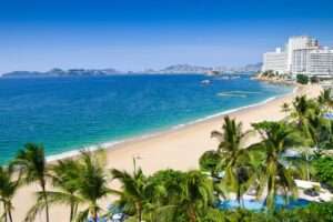 Open surf and golden sunset at Revolcadero Beach, with luxury resorts lining the horizon.